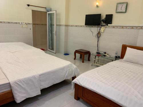 a bedroom with two beds and a tv on the wall at Cơ sở 2 - Hà Hùng Panorama Hotel Cho thuê nhà nguyên căn 3 phòng ngủ và bếp gần chợ đêm in Ha Tien