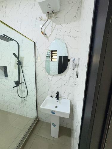 een witte badkamer met een wastafel en een douche bij Oaksvale Homes in Enugu