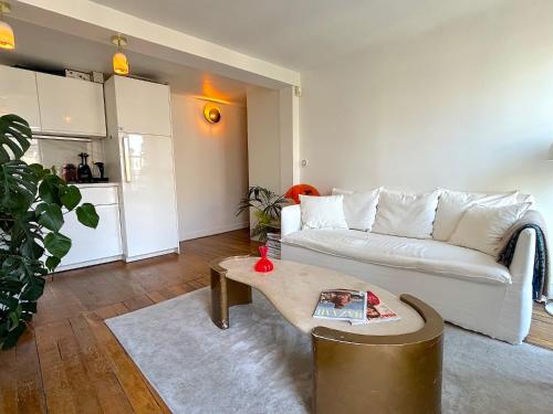 un salon avec un canapé blanc et une table dans l'établissement L'appartement Colombier, à Paris
