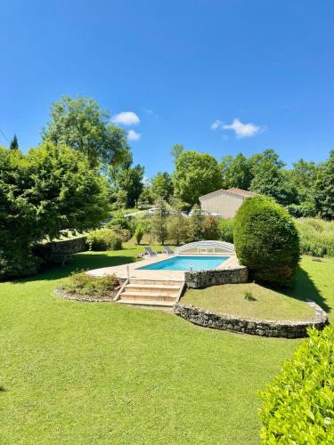une cour avec une piscine et une pelouse dans l'établissement Maison de Charme avec Piscine - Le Cocon de La Bastide, à La Bastide-de-Sérou