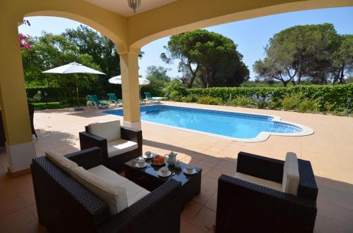 un patio con una piscina con sillas y una mesa en Bonita, en Quarteira