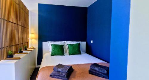 - une chambre avec des murs bleus et un lit avec des oreillers verts dans l'établissement Le Voltaire, Joli Studio, proximité de la Gare et du Centre, Climatisé, à Sète