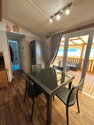 une salle à manger avec une table et des chaises en verre dans l'établissement Mobil-home 6 personnes 2CH 44m2, à Arreau