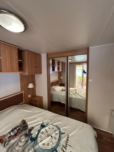 Cette chambre dispose d'un lit avec un réveil. dans l'établissement Mobil-home 6 personnes 2CH 44m2, à Arreau
