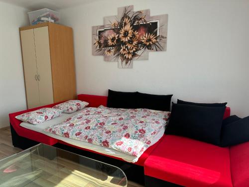 a red bed and a red couch in a room at Apartma Rekar - a house, where you can relax in the embrace of nature in Jesenice
