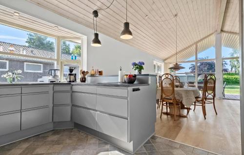 a kitchen with white cabinets and a dining room with a table at Holiday Home Hejsager Strandby I in Kelstrup Strand
