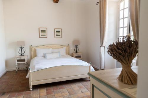 a bedroom with a white bed and two windows at Château les Crostes in Lorgues