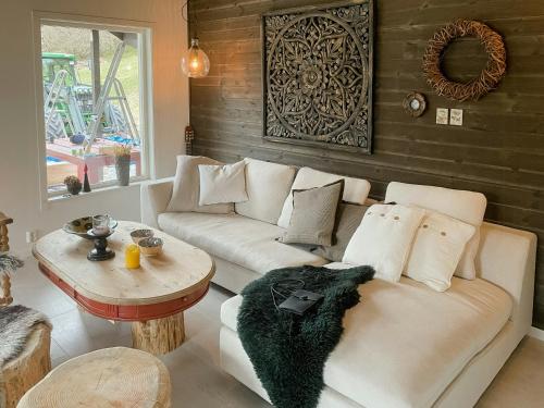 un soggiorno con un divano bianco e un tavolo di Cozy Modern Cabin In West Norway With View a Davik