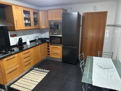 a kitchen with wooden cabinets and a black refrigerator at Sea View Andrade 3 Bedroom House in Gaula