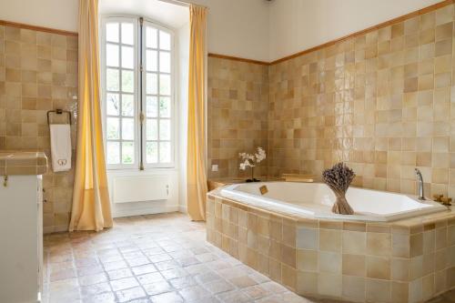 a large bathroom with a tub and a window at Château les Crostes in Lorgues