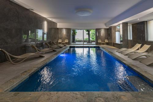 - une piscine avec des chaises dans une chambre d'hôtel dans l'établissement Hotel Munsch Restaurant & Wellness, Colmar Nord - Haut-Koenigsbourg, à Saint-Hippolyte