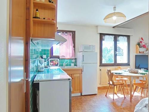Il comprend une cuisine équipée d'un réfrigérateur et d'une table avec des chaises. dans l'établissement Charmant appart 3 pièces avec mezzanine et ascenseur, 6 pers, centre village, proche commerces, navettes - FR-1-241-138, au Grand-Bornand