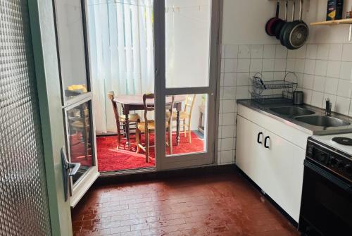 une cuisine avec une porte ouverte sur une table avec des chaises dans l'établissement La Loggia, à Sète