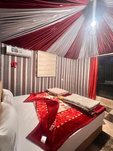 a bedroom with a bed with a red blanket at Layla Wadi Rum in Disah
