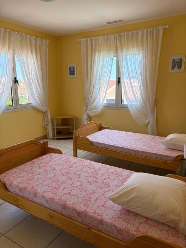 une chambre avec deux lits et deux fenêtres dans l'établissement Villa avec piscine a 6 min du port Saint-Cyprien, à Saint Cyprien Plage