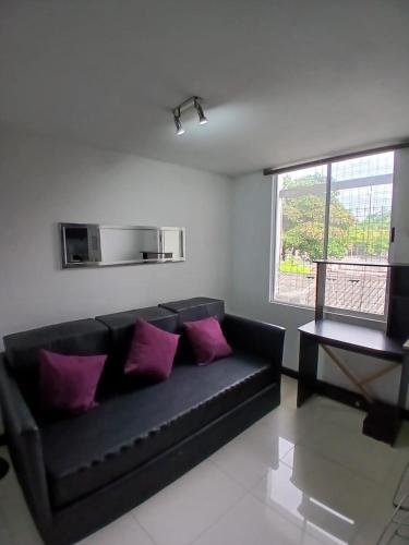 a black couch in a living room with purple pillows at Hotel Plaza Norte Cali in Cali