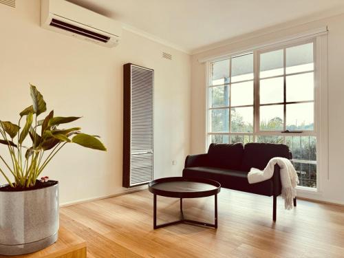 a living room with a black couch and a table at Haven St Johns in Narre Warren