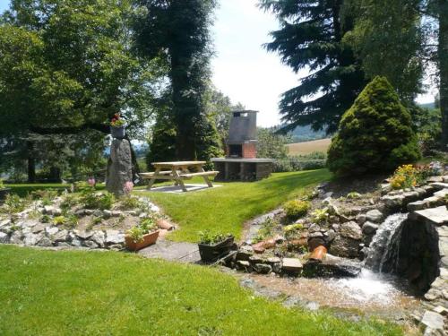 a garden with a waterfall and a picnic table at Gite de la source in Noirétable
