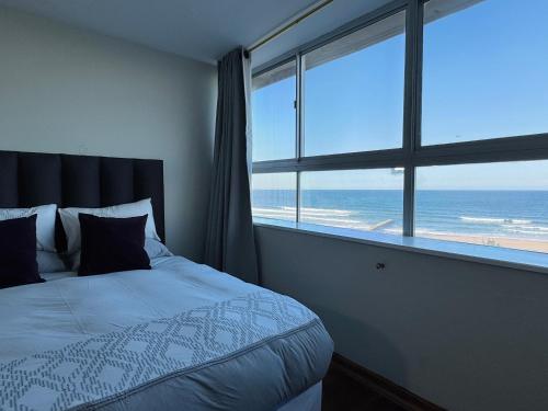 a bedroom with a bed with a view of the ocean at Accommodation Front - Edgy Beachfront 2 Sleeper with Stunning View in Durban