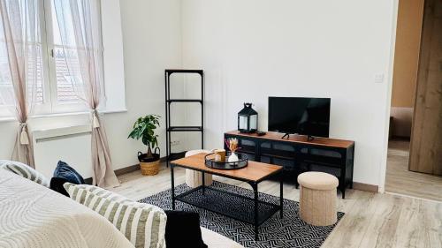 un salon avec une télévision et une table basse dans l'établissement L'Instant Bohème - Parking - Proche gare & Wifi, à Sainte-Savine
