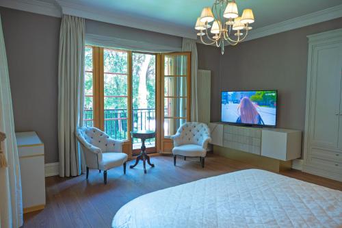 a bedroom with a bed and two chairs and a television at Stately Home in Magdalenka Warsaw in Magdalenka
