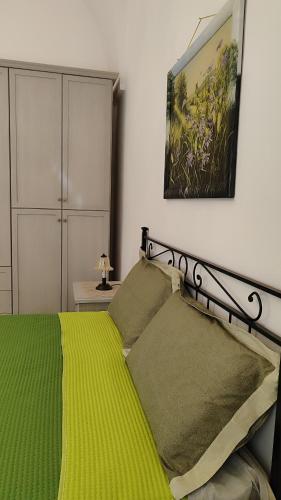 a bedroom with a green bed with a painting on the wall at Casa Marcel in Ugento