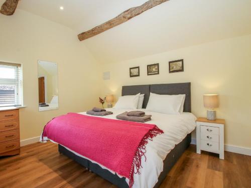 a bedroom with a large bed with a red blanket at The Old Piggery in Shifnal