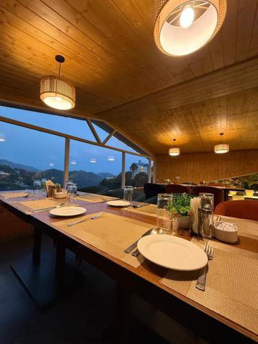 a long wooden table with plates and glasses on it at ARNISA Kasauli - A Boutique Hotel in Kasauli