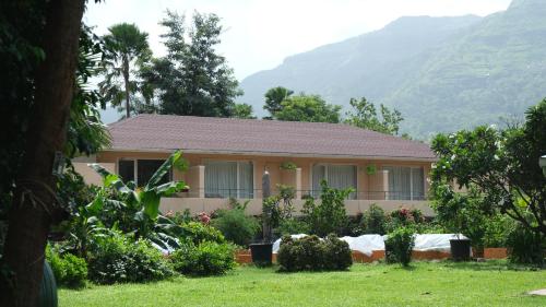 a house with a garden and mountains in the background at The Riverstone Agro Farm in Vajapūr