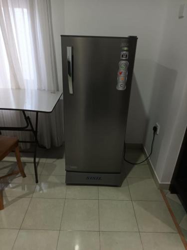 a black refrigerator sitting on a floor next to a table at Comfortable Stay in Colombo in Rajagiriya