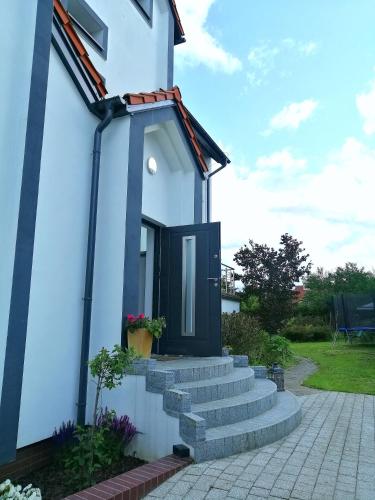 a small white house with a black door at Pokoje nad jeziorem Gdańsk in Gdańsk
