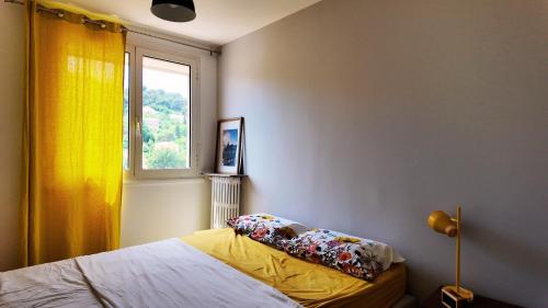 - une chambre avec un lit doté d'un rideau jaune et d'une fenêtre dans l'établissement Le Grand Bleu, à Sète