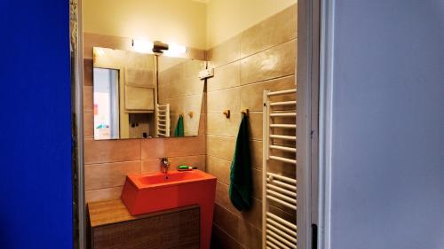 La salle de bains est pourvue d'un lavabo rouge et d'un miroir. dans l'établissement Le Grand Bleu, à Sète