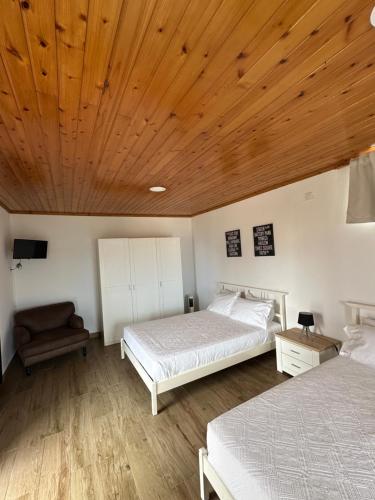 a bedroom with two beds and a wooden ceiling at Sara Village in São Roque do Pico