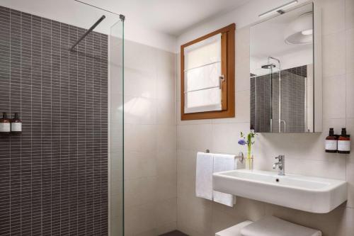a bathroom with a sink and a glass shower at Tivoli Portopiccolo Sistiana Apartments in Sistiana