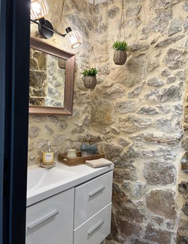 une salle de bain avec un lavabo et un mur en pierre dans l'établissement L'Ecrin de Mérindol, à Mérindol