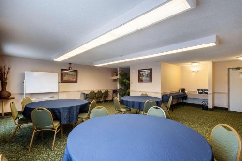 a conference room with blue tables and chairs and a whiteboard at SureStay Hotel by Best Western SeaTac Airport North in SeaTac