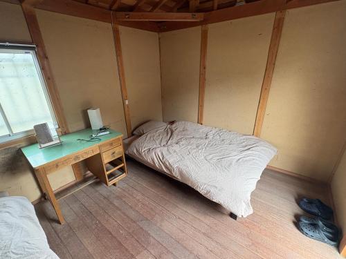 a room with a bed and a desk with a computer at guesthouse KIKUKO in Saijo
