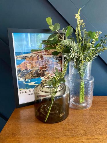 two vases with flowers on a table next to a picture at Carrick Retreat - Free off street parking in Carrickfergus