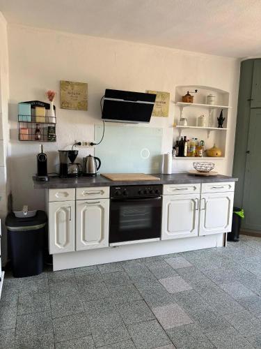 a kitchen with white cabinets and a stove top oven at Ferienhaus Eifel Lotti in Reuth