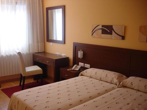 a bedroom with a bed and a desk and a chair at Hostal Acanto in Burgos