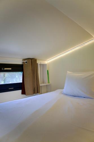 une chambre avec un grand lit blanc et une télévision dans l'établissement La Tiny House des Montagnes, à Verrens-Arvey