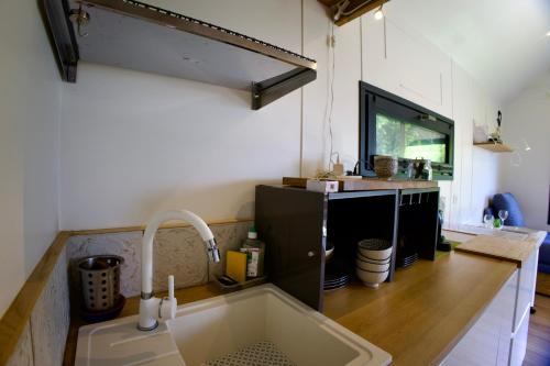 eine Küche mit Spüle und Fernseher in der Unterkunft La Tiny House des Montagnes in Verrens-Arvey