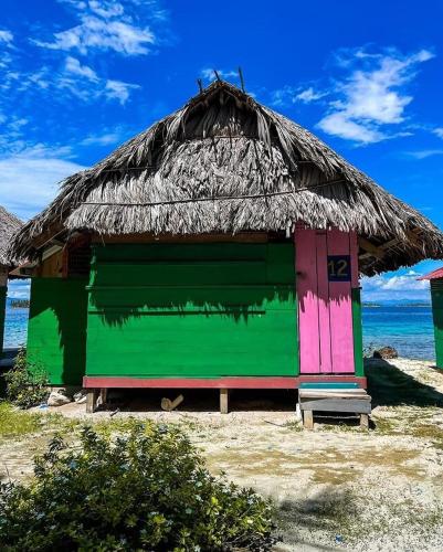 a hut with a thatched roof on a beach at Romantic Cabin on Diablo Island San Blas in Panama City