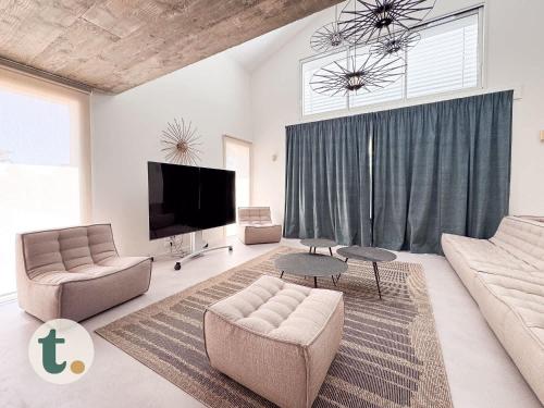 un salon avec un canapé et une télévision dans l'établissement Tranquiloue - La Maison de Gabriel - Puy du Fou, aux Herbiers