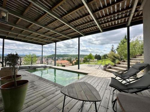 une terrasse avec une piscine, 2 chaises et une table dans l'établissement TheView, piscine et sauna, au Puy-en-Velay