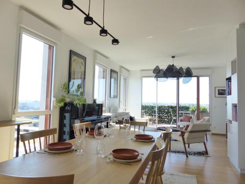 a dining room with a table with chairs and windows at Le Belvédère - Appartement de standing, 2 chambres et parking in Nantes