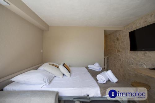 - une chambre avec un lit doté d'oreillers blancs et une télévision à écran plat dans l'établissement Studio in Villefranche, à Villefranche-sur-Mer