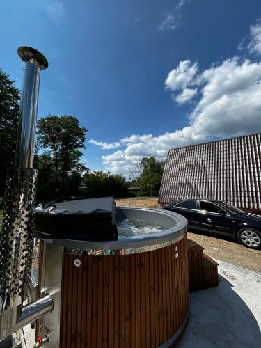 a hot tub sitting on a patio with a car at Casuțele de la răscruce in Uric
