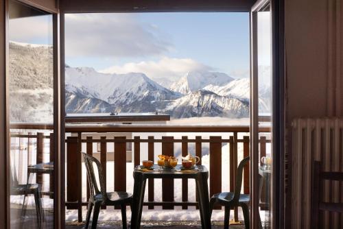 a table and chairs on a balcony with a view of mountains at Le Castillan in L'Alpe-d'Huez